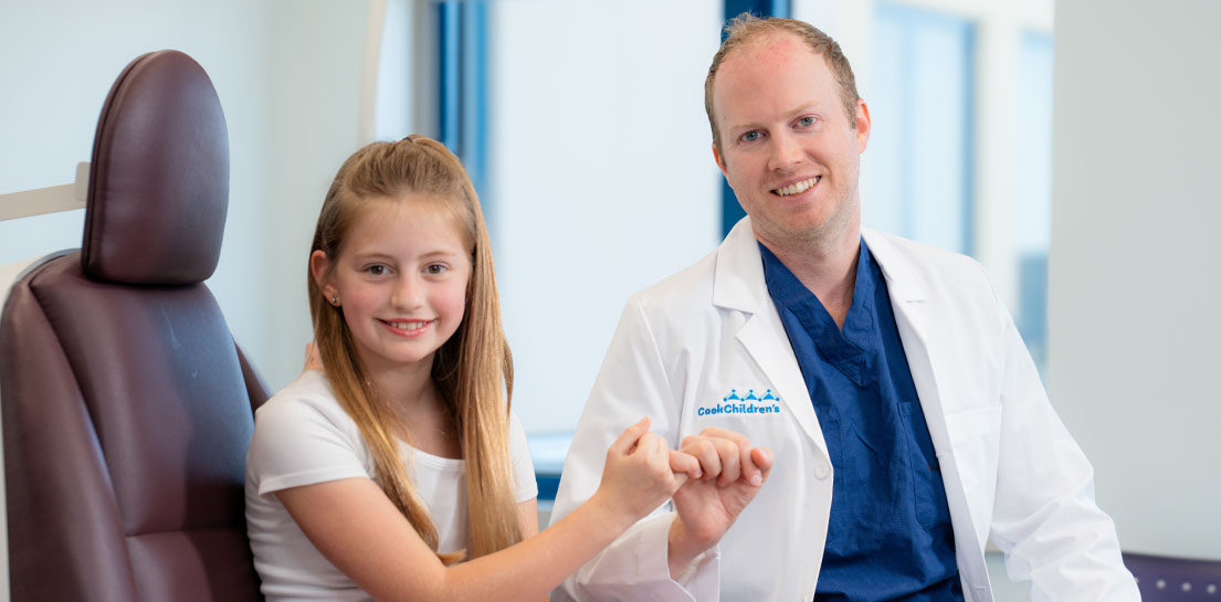 Smiling clinician and young patient sharing a pinky swear at Cook Children's Plastic Surgery Center